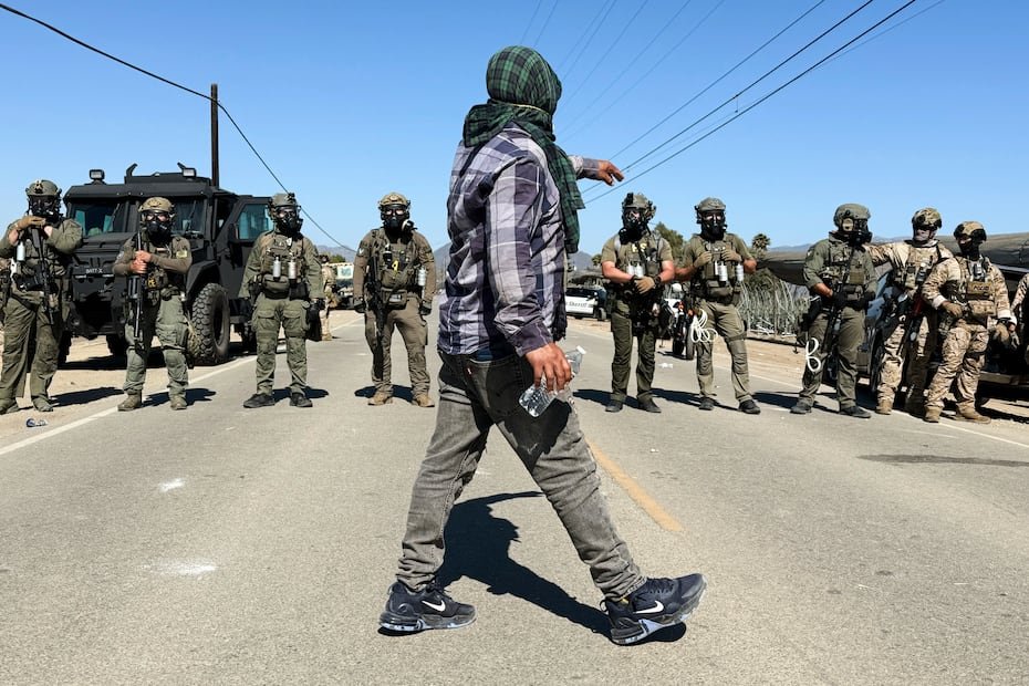Un manifestante camina frente a agentes federales que bloquean una carretera durante una redada migratoria, el jueves 10 de julio de 2025, en Camarillo, California.