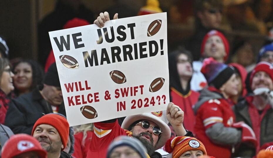 Fans sostienen un cartel con el ala cerrada de los Kansas City Chiefs, Travis Kelce, y Taylor Swift durante un partido de fútbol americano de la NFL entre los Kansas City Chiefs y los Cincinnati Bengals, el 31 de diciembre de 2023, en Kansas City, Missouri. (Foto AP/Peter Aiken)