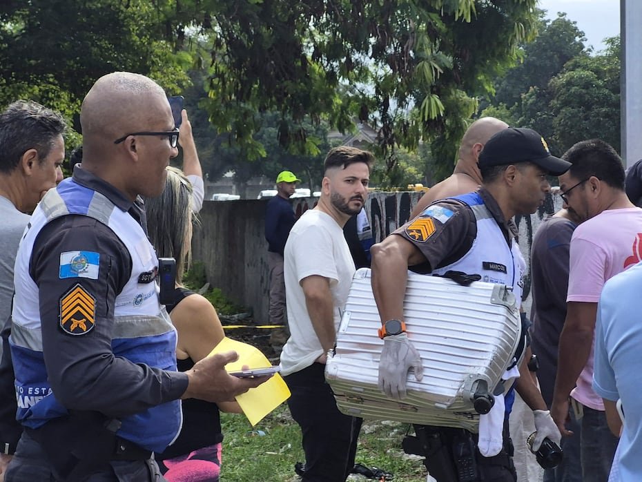 Un policía militar de Río de Janeiro transportando una maleta recuperada en el lugar donde ocurrió el accidente