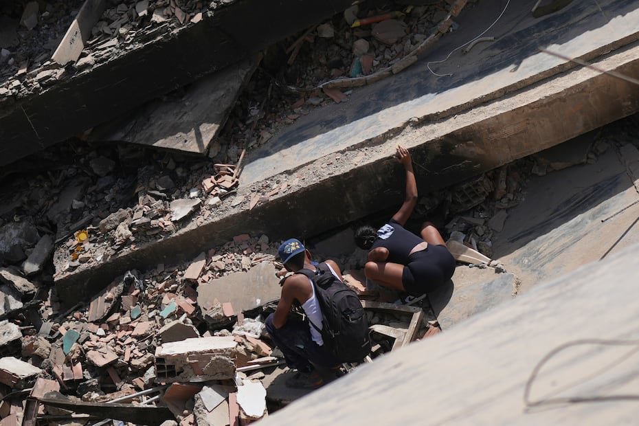 Arkelis Izaguirre (der) busca su hermano Manuel entre los escombros del edificio colapsado en La Guaira, Venezuela.
