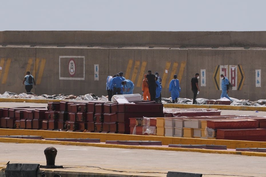 Trabajadores forenses colocan los cuerpos de las víctimas del terremoto en ataúdes en el puerto de La Guaira.