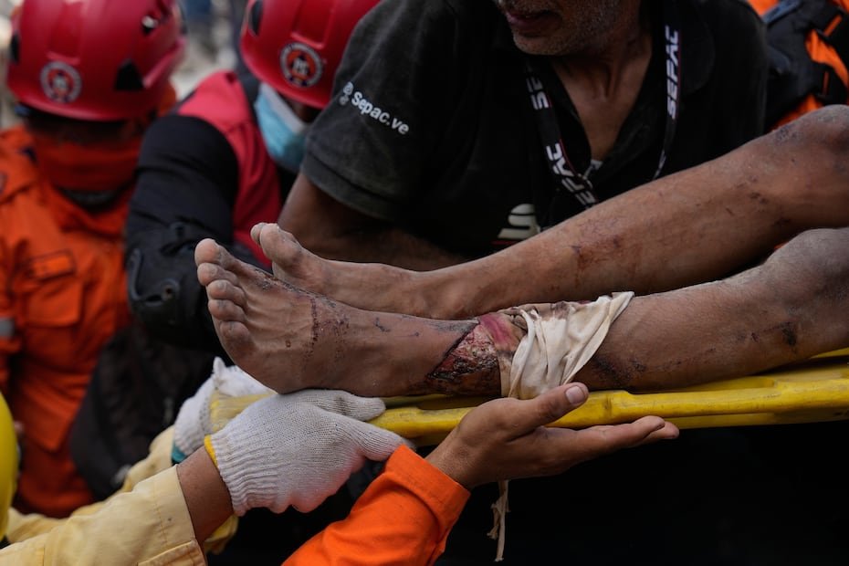 Rescatistas cargan a Patrick Vargas después sacarlo de los escombros, dos días después de los terremotos en Catia la Mar, Venezuela.