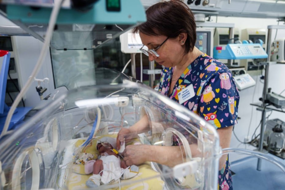 La enfermera Victoria Bohdanova cambia el pañal a un bebé prematuro dentro de una incubadora de temperatura controlada.