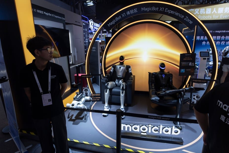 Un trabajador observa varios robots humanoides exhibidos por Magiclab, una empresa china de inteligencia artificial incorporada y robots humanoides