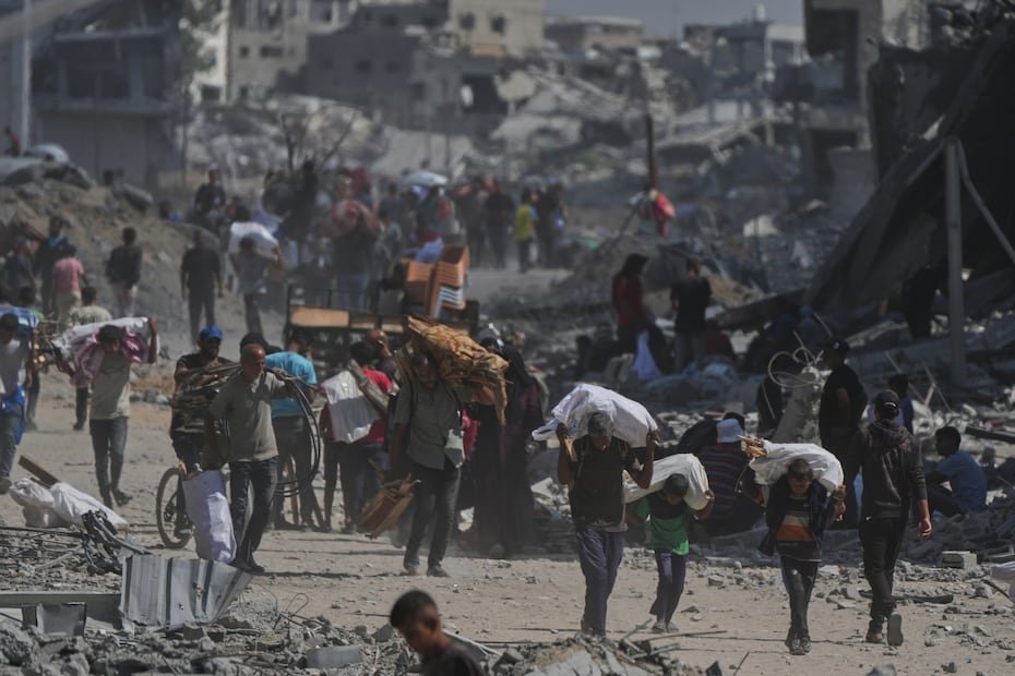 Palestinos desplazados caminan con sus pertenencias junto a edificios destruidos mientras regresan a sus hogares en Khan Younis, al sur de la Franja de Gaza, después de que Israel y Hamás acordaran una pausa en la guerra y la liberación de los rehenes restantes.
