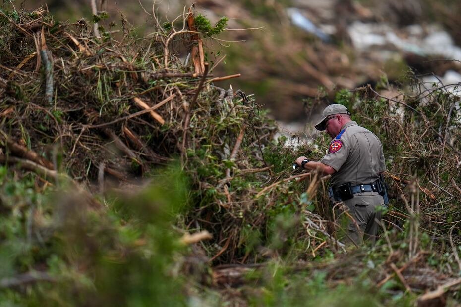 Un funcionario del Departamento de Salud Pública de Texas busca en las orillas del río Guadalupe cerca del campamento Mystic después de una inundación repentina, el sábado.