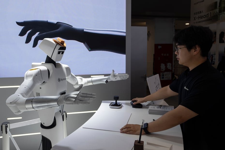 Un trabajador prepara un robot para demostrar el funcionamiento de sus manos en el pabellón de la empresa china Xynova