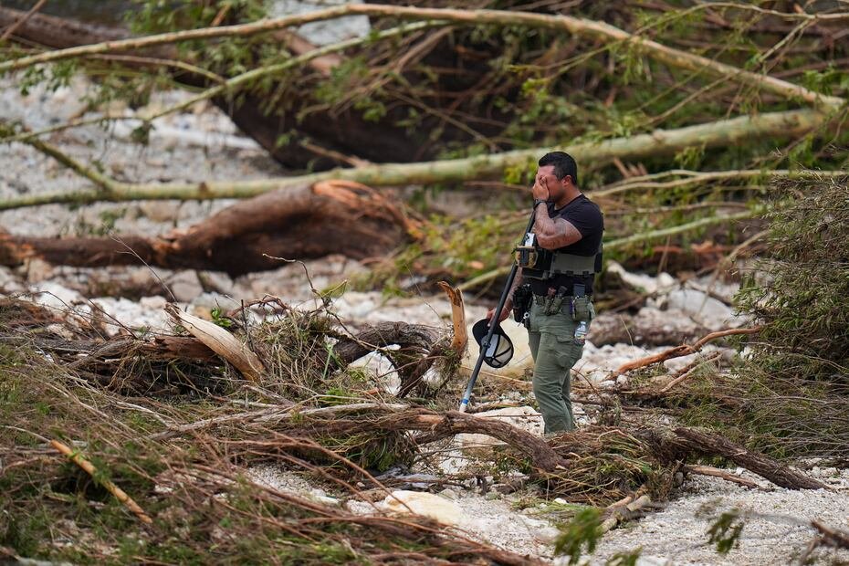 Un agente de la policía del condado hace una pausa mientras busca en las orillas del río Guadalupe cerca del campamento.