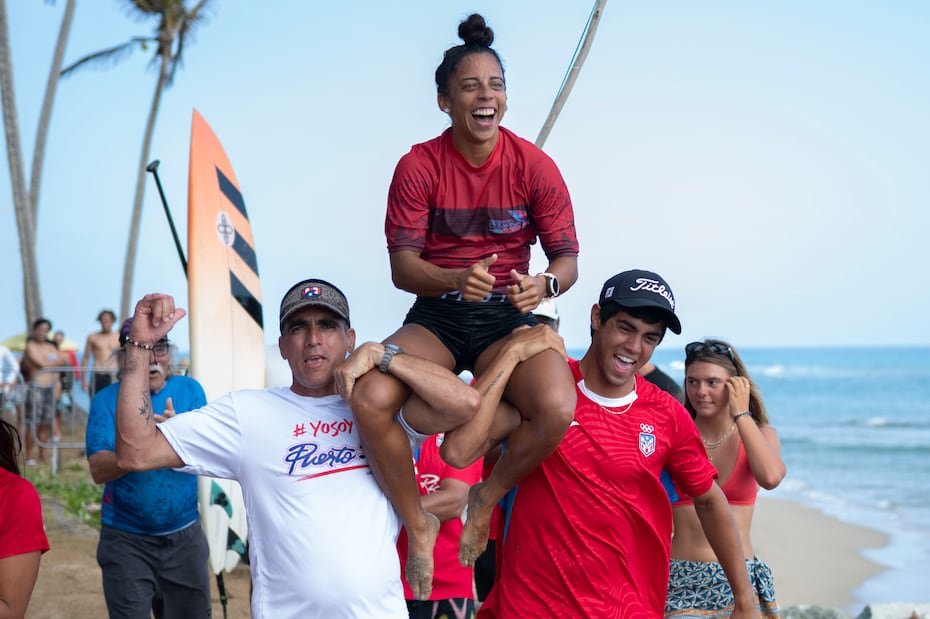 Mariecarmen Rivera es cargada por sus compañeros de delegación de surf.
