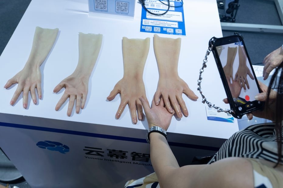 Una mujer toma fotografías de una piel realista para manos robóticas exhibida por Yunmu Intelligence Manufacturing