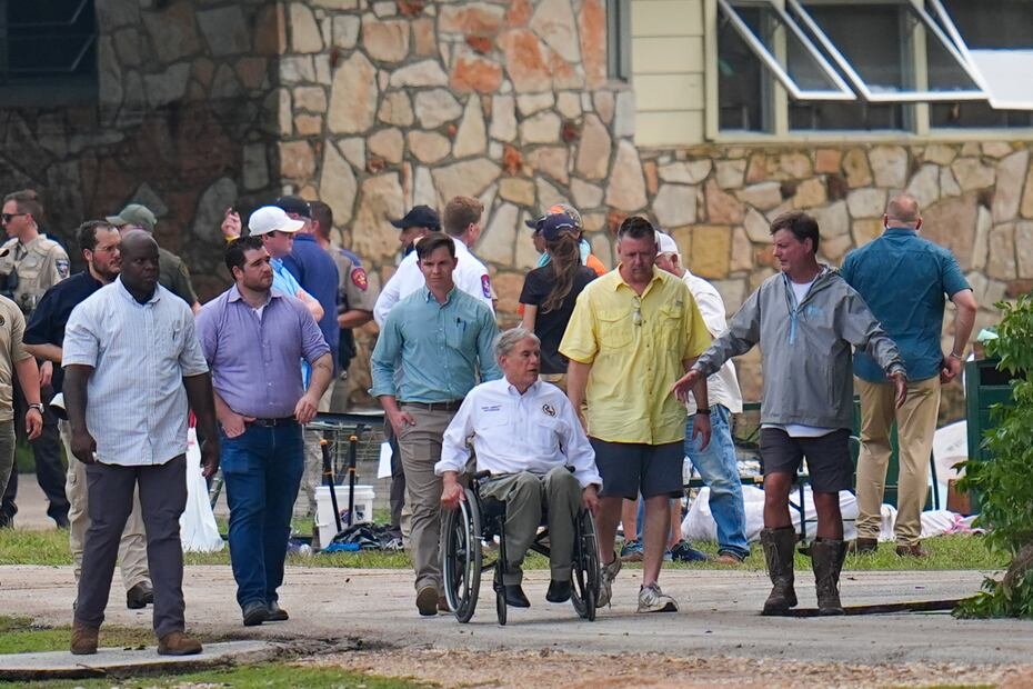 El gobernador de Texas, Greg Abbott, al centro, visitó el sábado los predios del campamento Mystic para ver los daños causados por las inundaciones.