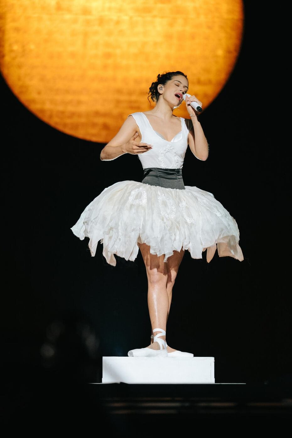 La cantante española viste un conjunto de Dior de color marfil compuesto por una camiseta sin mangas de punto de cuello redondo y una falda tutú de organza con medallones inspirados en hojas bordados con lentejuelas blancas decorativas y abalorios, que ceñe con un fajín negro.