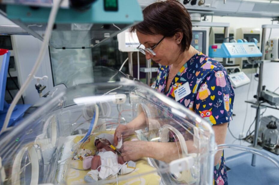 La enfermera Victoria Bohdanova cambia el pañal a un bebé prematuro dentro de una incubadora de temperatura controlada.
