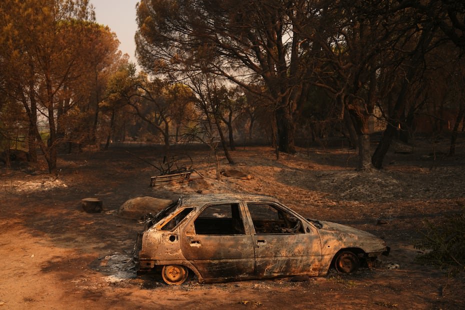 Un automóvil calcinado por un incendio forestal en la provincia española de Ávila, mientras el fuego continúa propagándose.