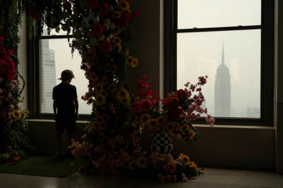 Una persona mira por la ventana del mirador "Top of the Rock" mientras el humo de los incendios forestales se cierne sobre Nueva York.