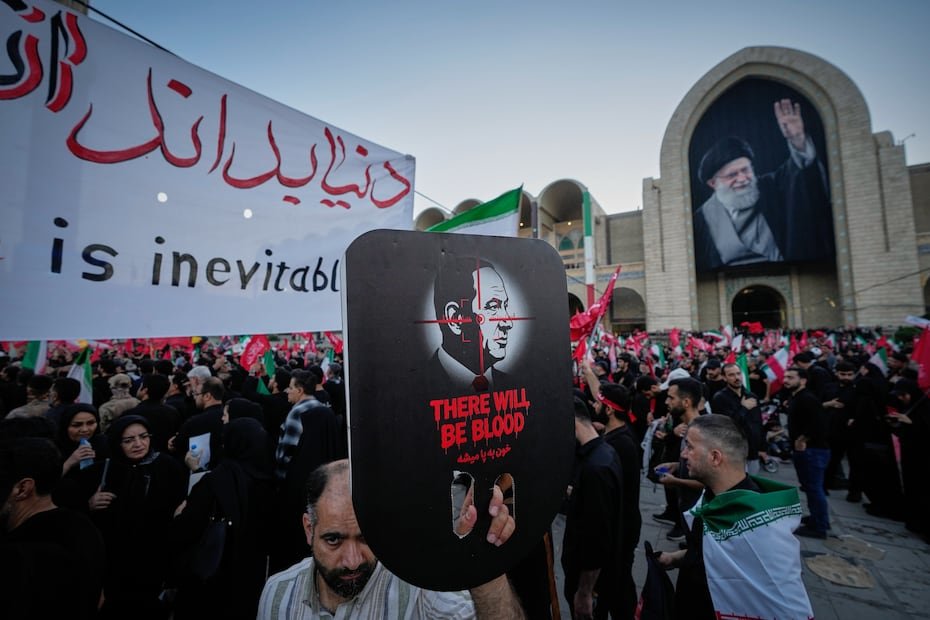 Un doliente sostiene un cartel con la imagen del primer ministro israelí, Benjamin Netanyahu, sobre la cual aparece una mira telescópica y las palabras "Habrá sangre", durante las ceremonias fúnebres.