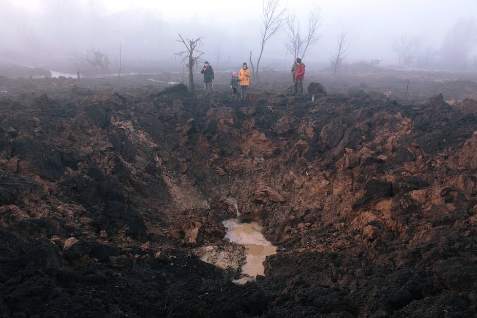 Los lugareños se reúnen alrededor de un cráter de bombardeo tras el impacto de un cohete en el barrio de Pisochyn.