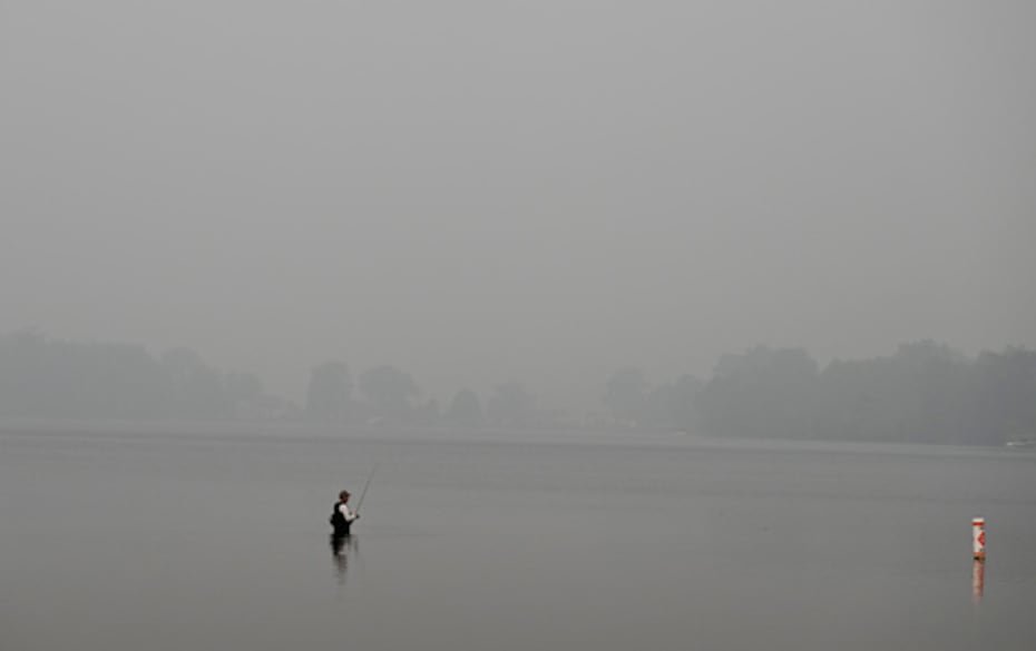 El humo de los incendios forestales envuelve el lago Vandercook mientras un pescador prueba suerte el jueves 16 de julio de 2026, cerca de Jackson (Michigan).
